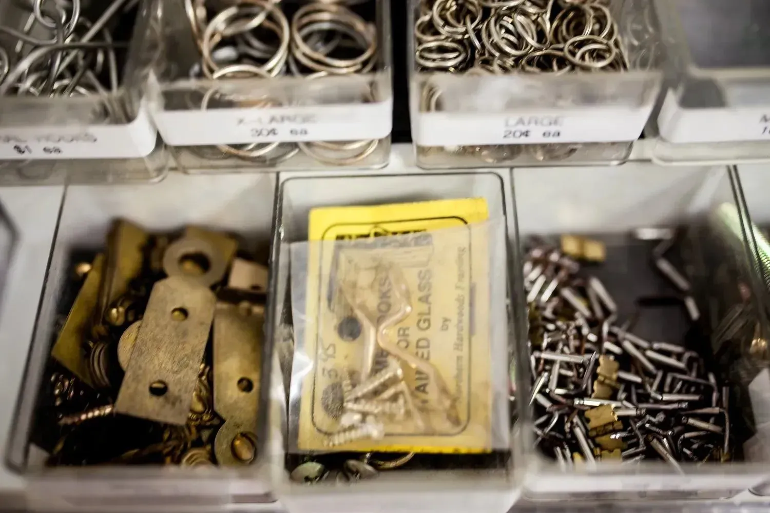 Close-up of a drawer with compartments holding various jewelry-making supplies, including rings, clasps, and small metal pieces.