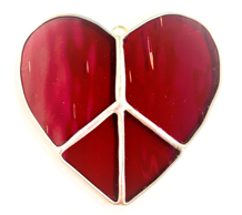 Stained glass art in a shop window, including a face, tree, and other colorful designs.