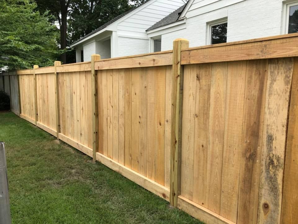 A wooden fence is in the backyard of a house.