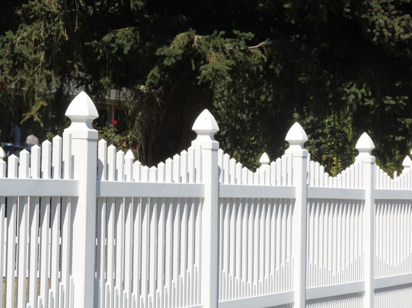 A white picket fence with trees in the background