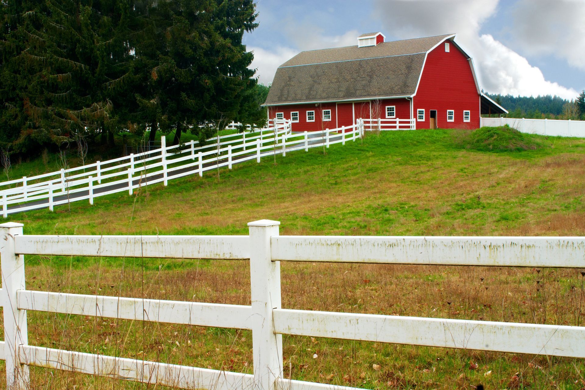 A red barn with a white fence in front of it