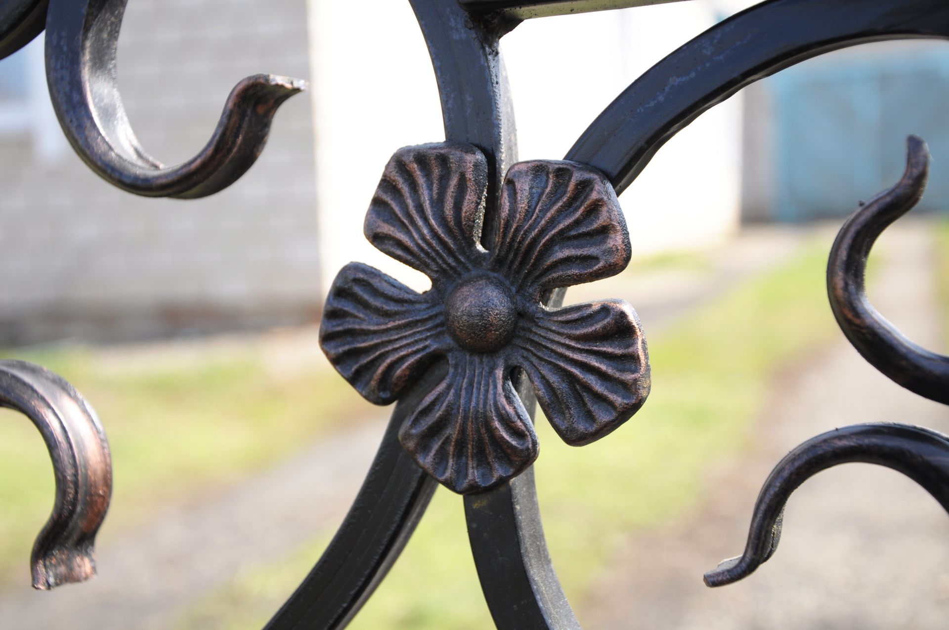 A close up of a wrought iron flower on a fence