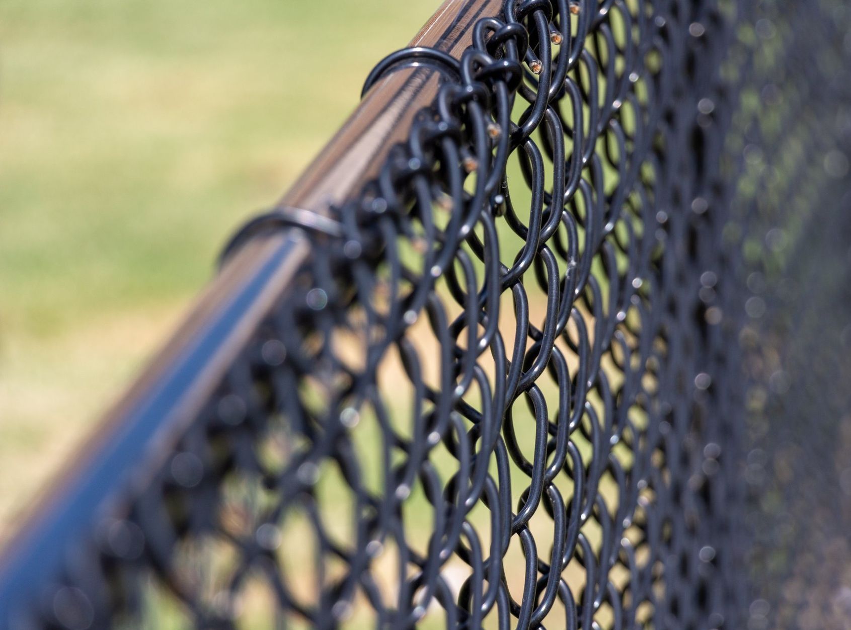 A close up of a black chain link fence with a blue railing.