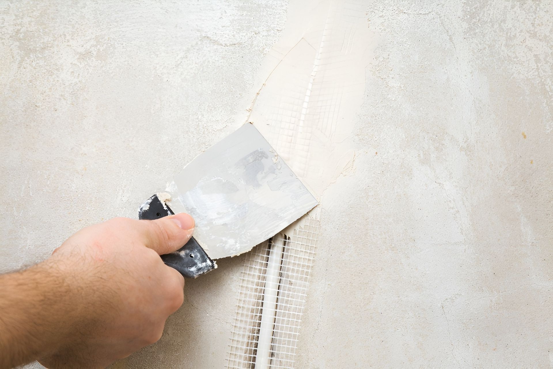 Hand Using a Putty Knife to Apply Compound Over Mesh Tape in A Wall Seam — Frenchy’s Plaster & Paint in Bellamack, NT