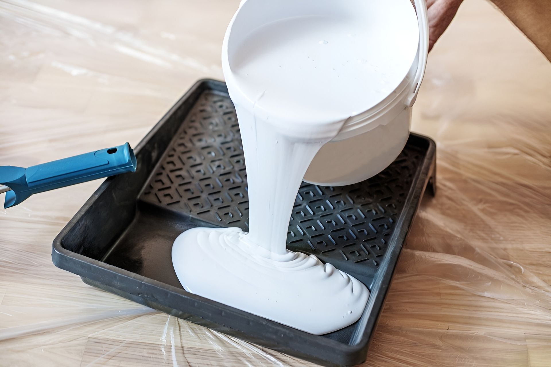 Person Pouring White Paint from A Bucket Into a Paint Tray on A Surface — Frenchy’s Plaster & Paint in Bellamack, NT