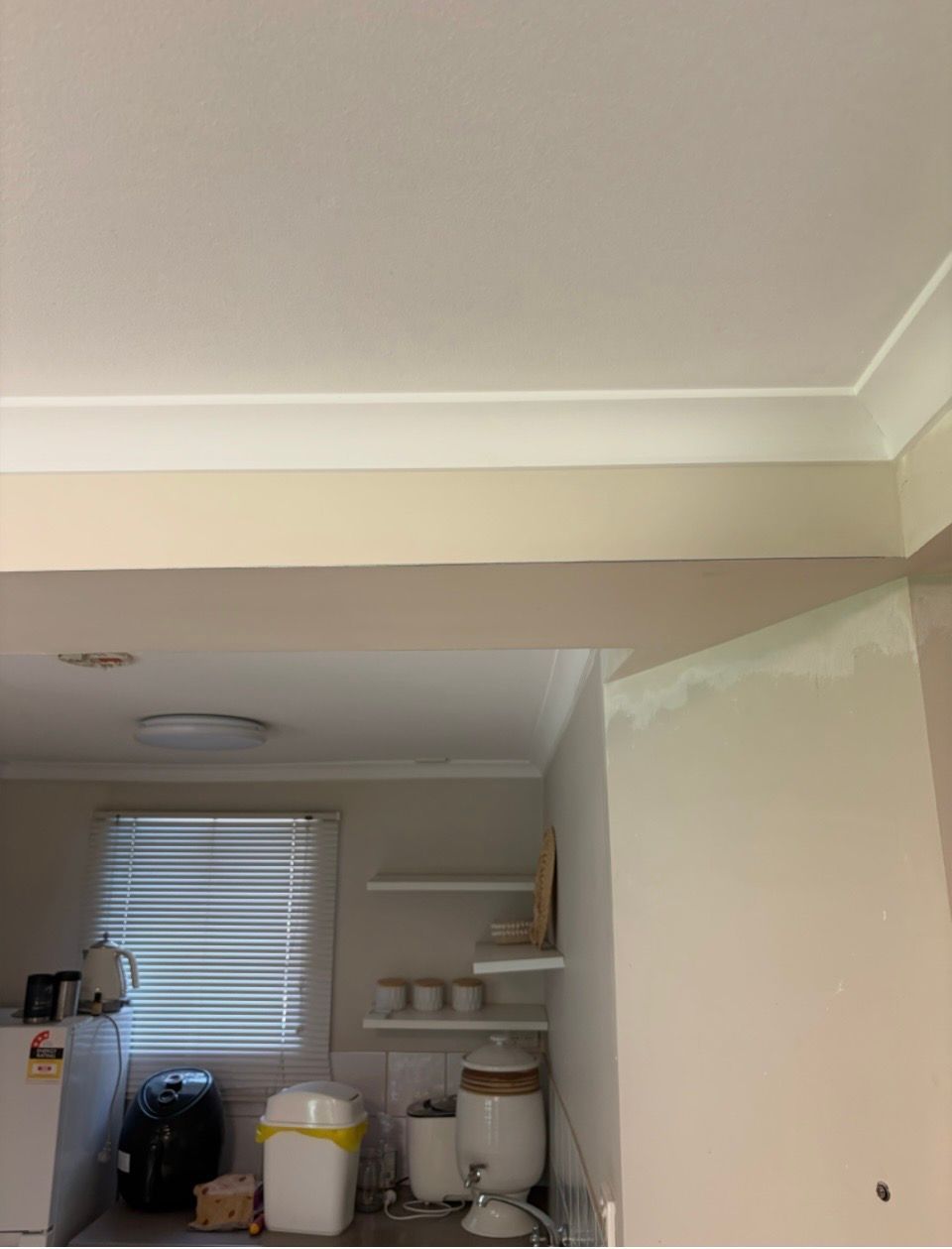 A ceiling corner showing a horizontal crack where the wall meets the ceiling beam, with some patch work on the side wall. — Frenchy’s Plaster & Paint in Bellamack, NT