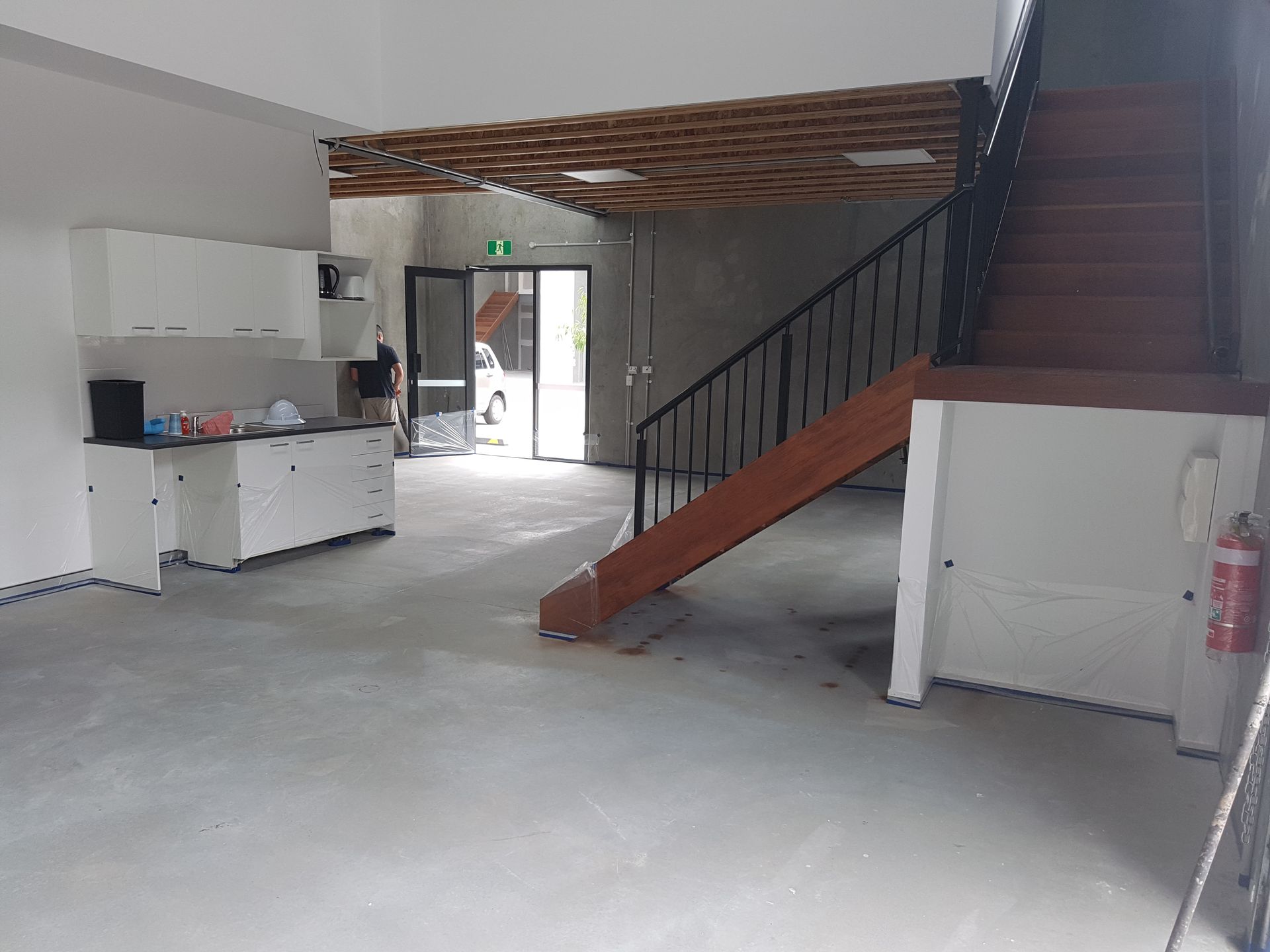 Interior view of a building with a staircase, white cabinets, and an open doorway.
