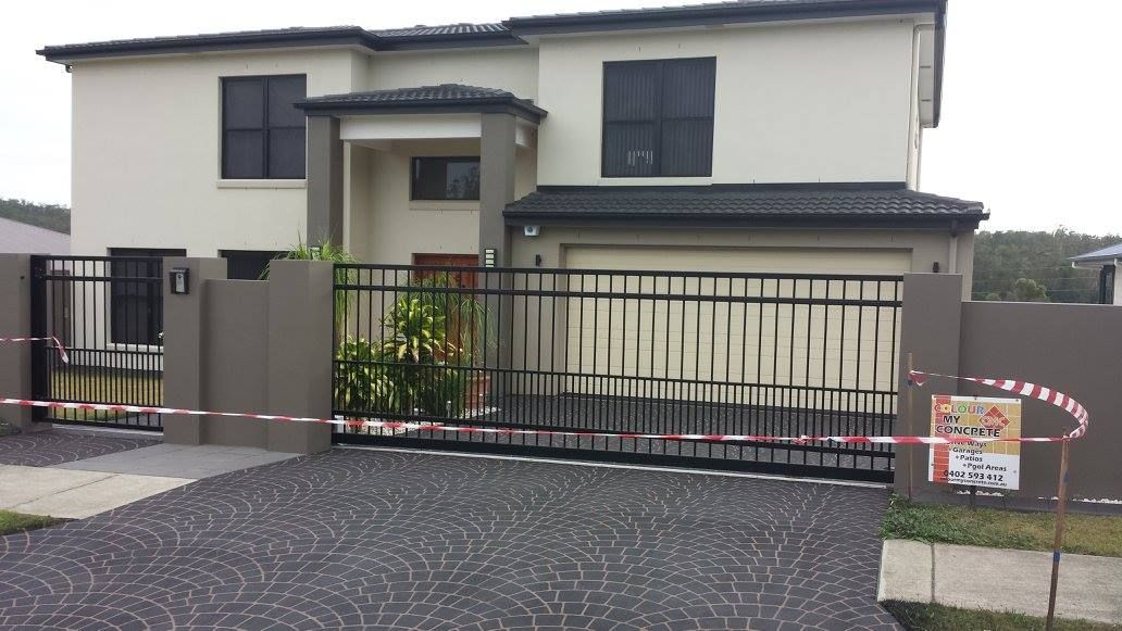 Two-story house with black gate and driveway. House is beige with dark-framed windows. Red and white tape blocks entry.