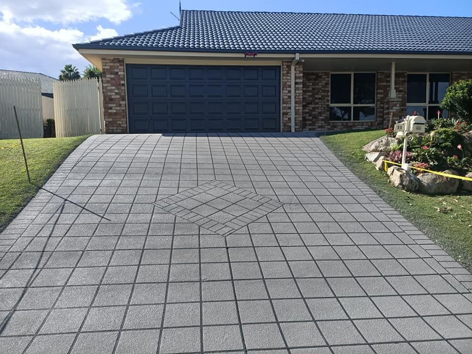 A gray brick driveway leads up to a house with a gray garage door.