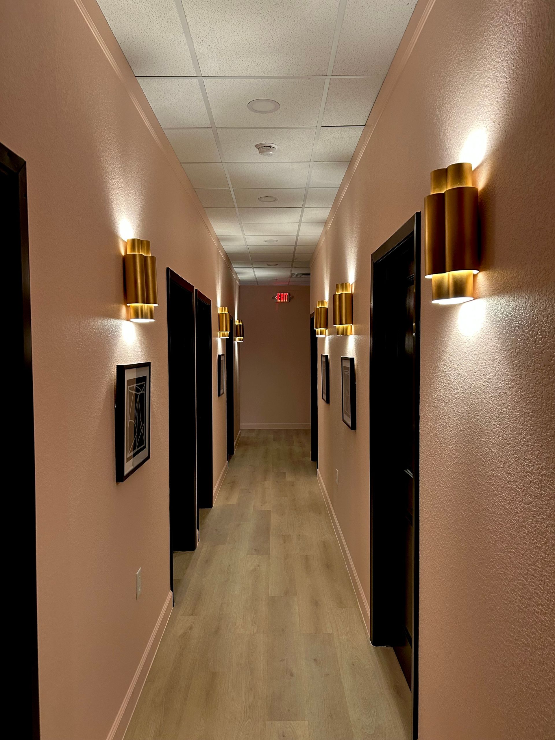 A long hallway with a red exit sign on the ceiling