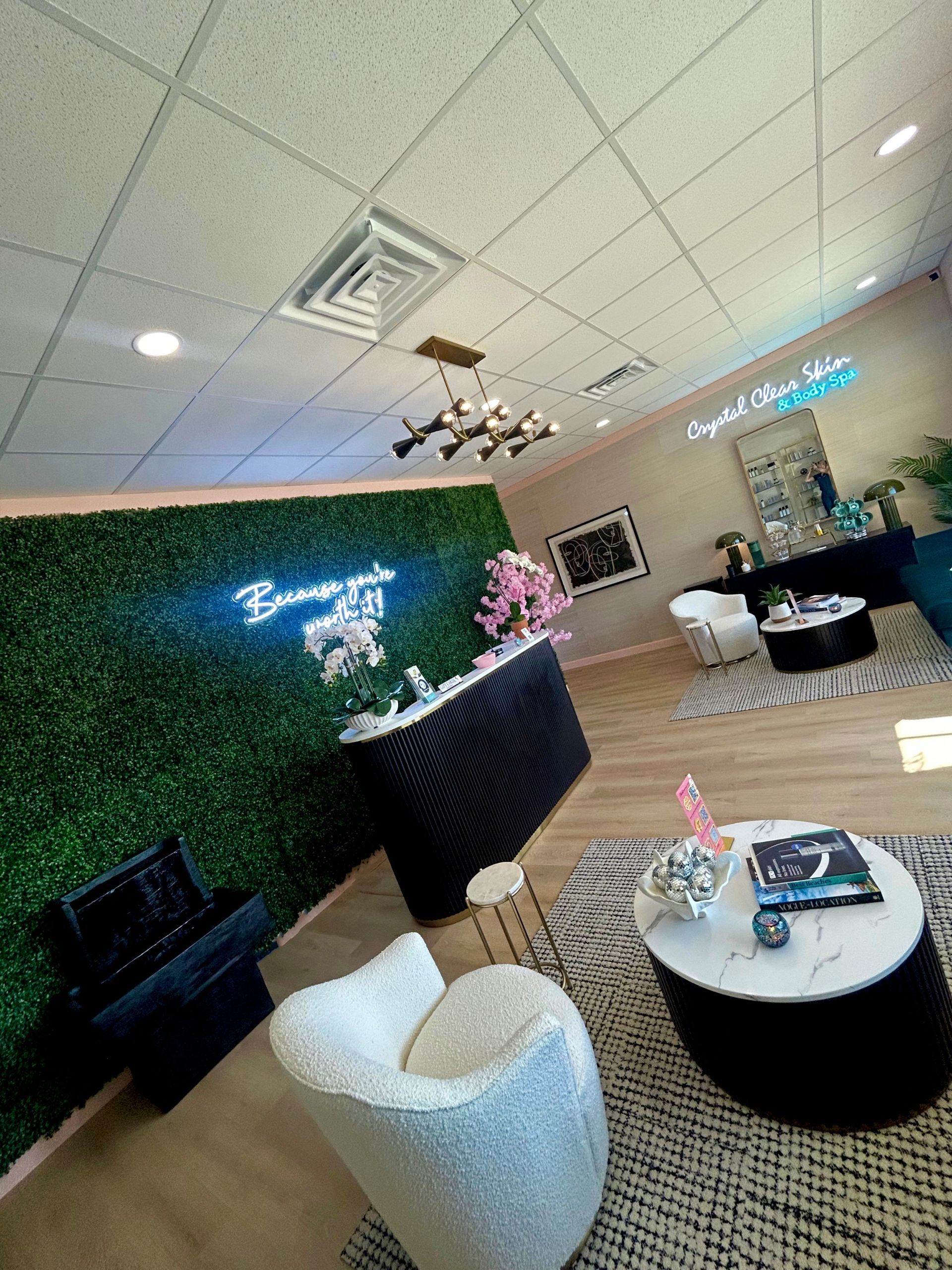 A living room with a green wall , chairs , tables and a neon sign.