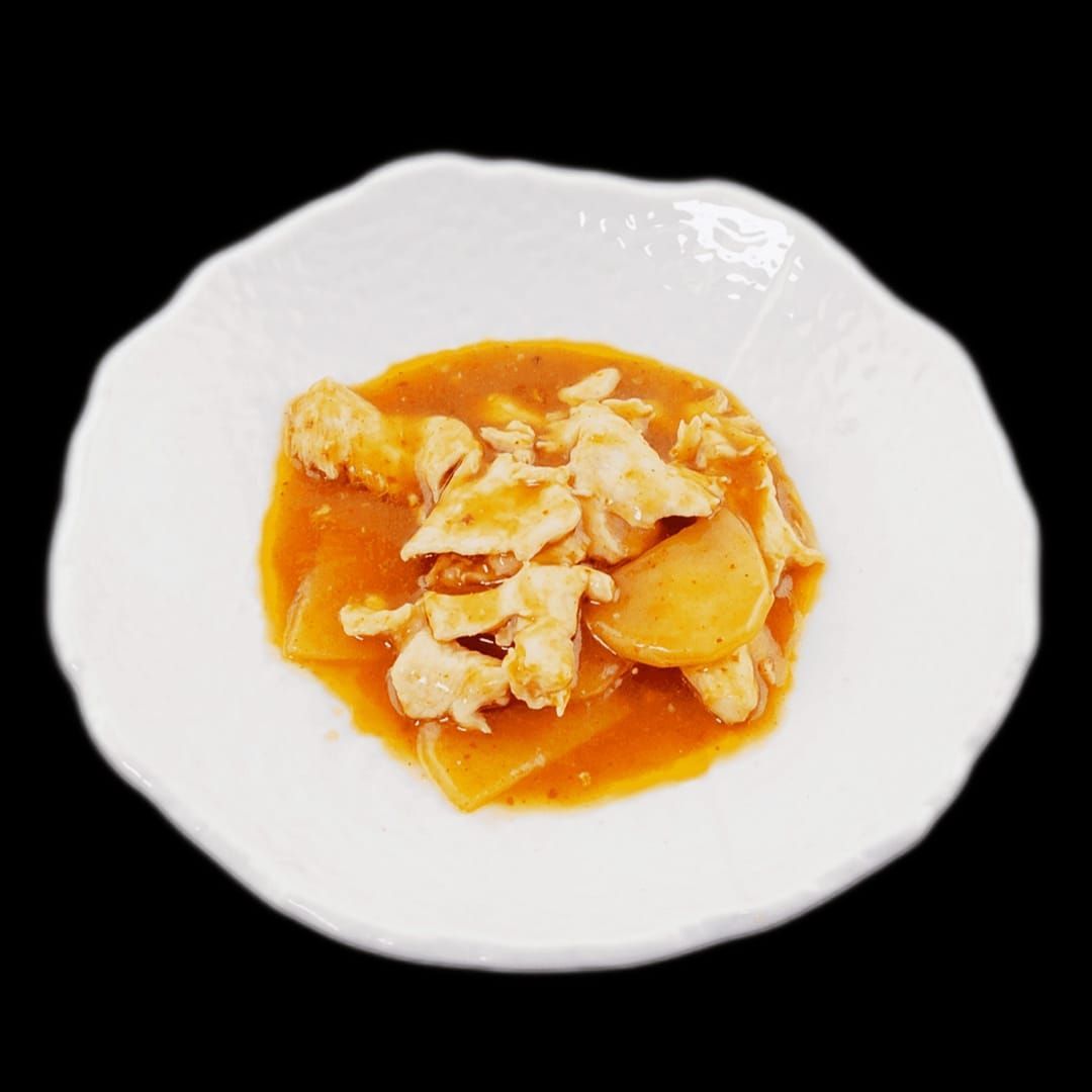 Un piatto bianco con pollo e salsa su uno sfondo nero.