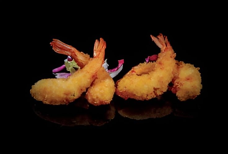 Un primo piano di gamberi fritti su una superficie nera.