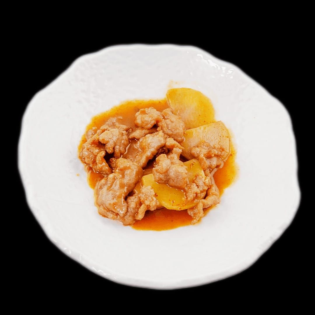 Un piatto bianco con carne e salsa su uno sfondo nero.