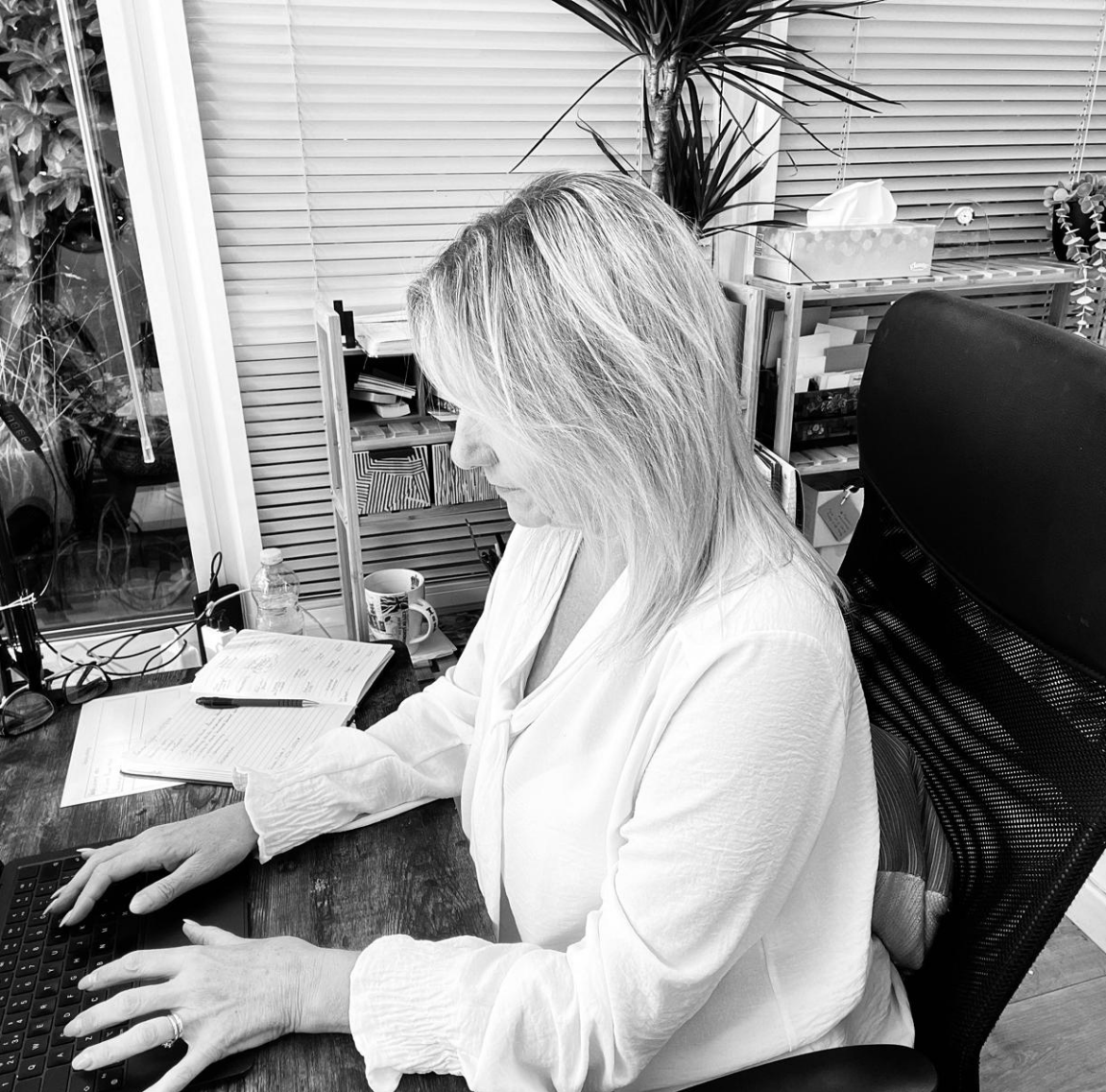 Pam Shanker is sitting at a desk using a laptop computer.