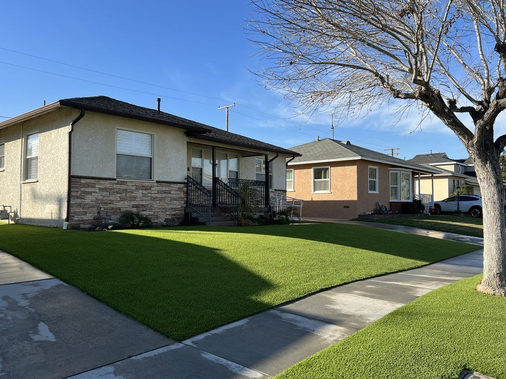 A house with a lush green lawn and a tree in front of it.