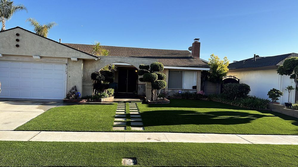 A house with a lush green lawn and a white garage door