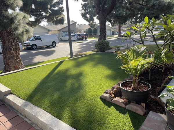 A white van is parked on the side of the road next to a lush green lawn.