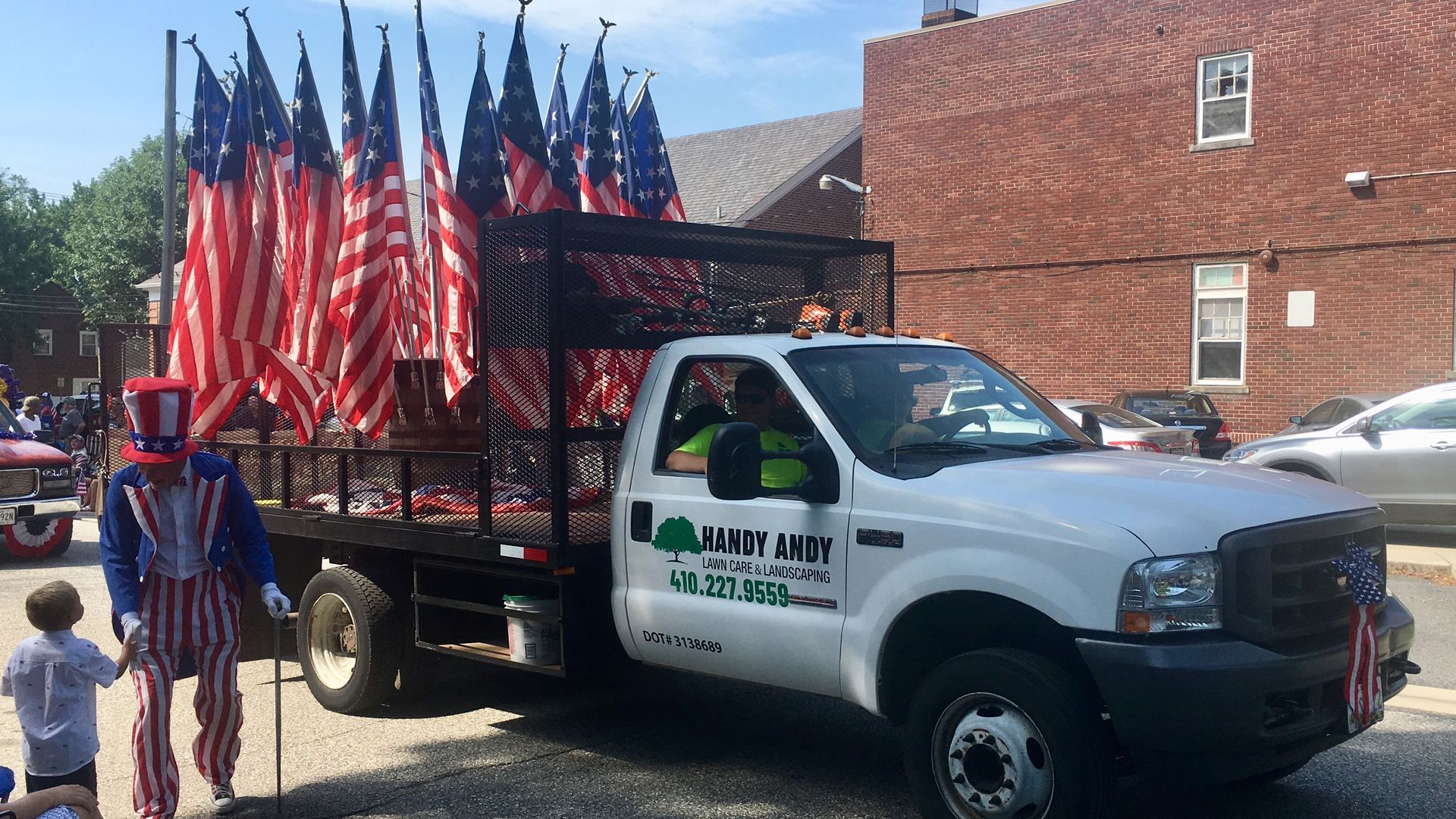 A white truck with american flags on the back is parked in front of a brick building.