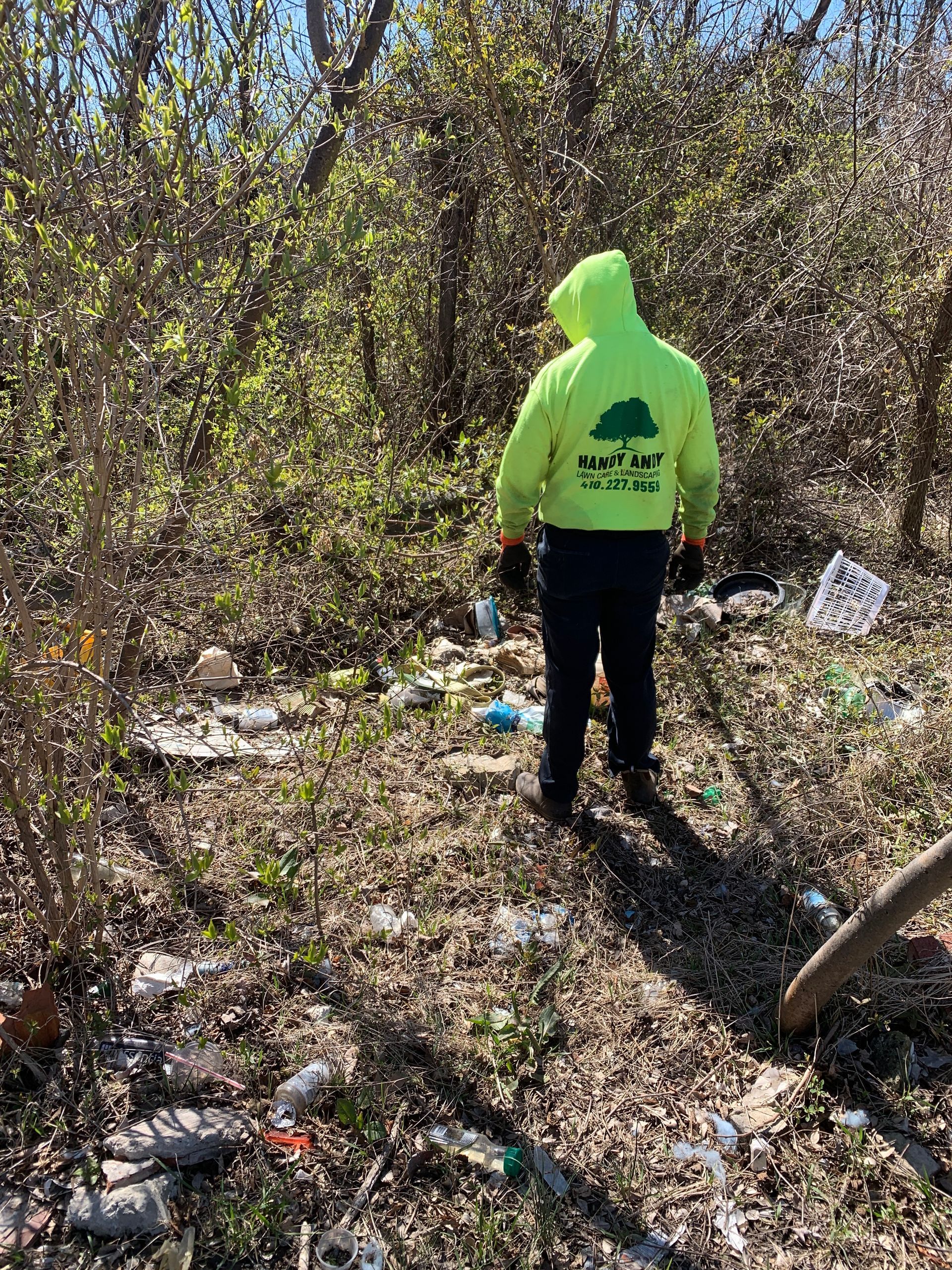 A man in a yellow hoodie is standing in the middle of a forest.