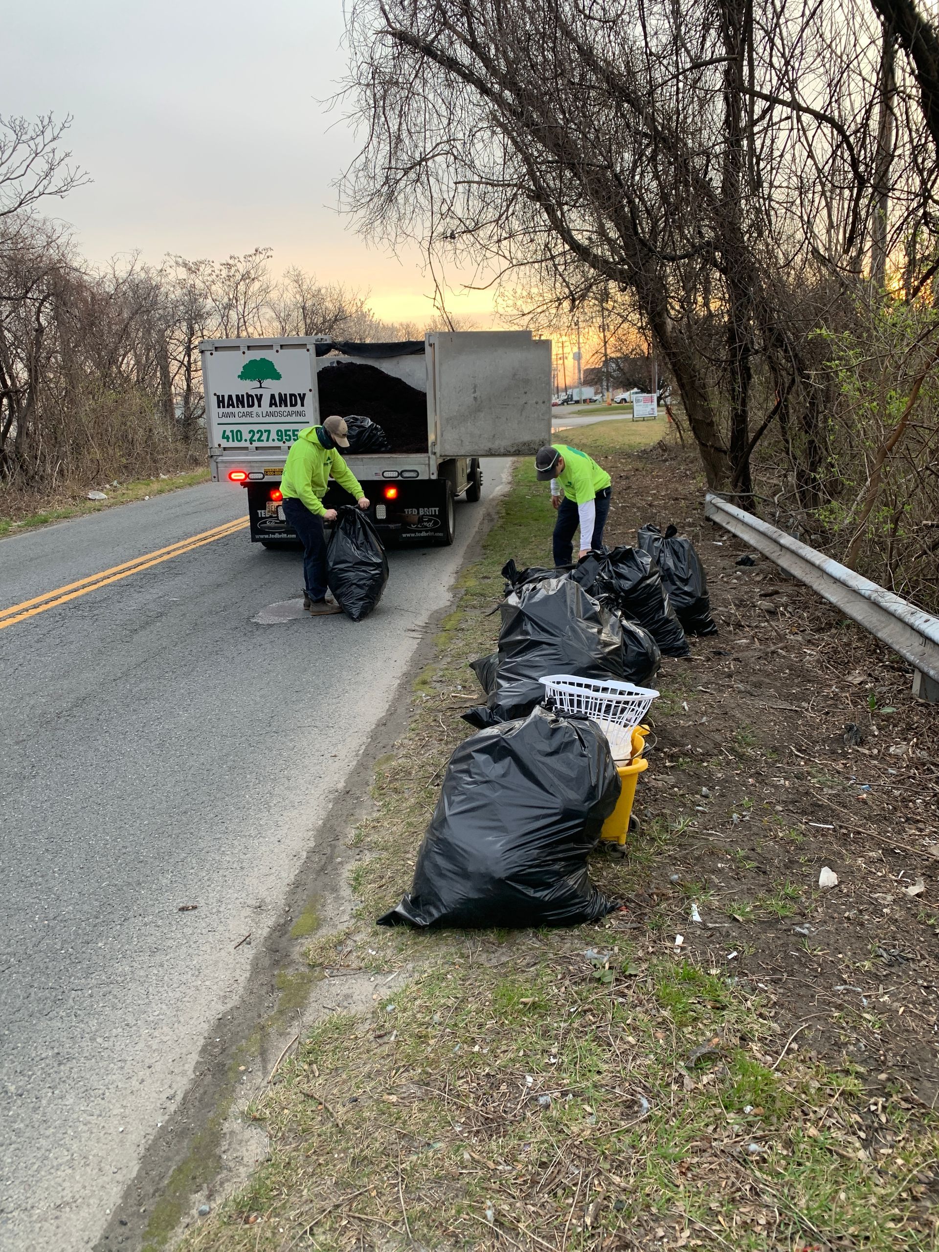 A group of people are cleaning the side of a road.