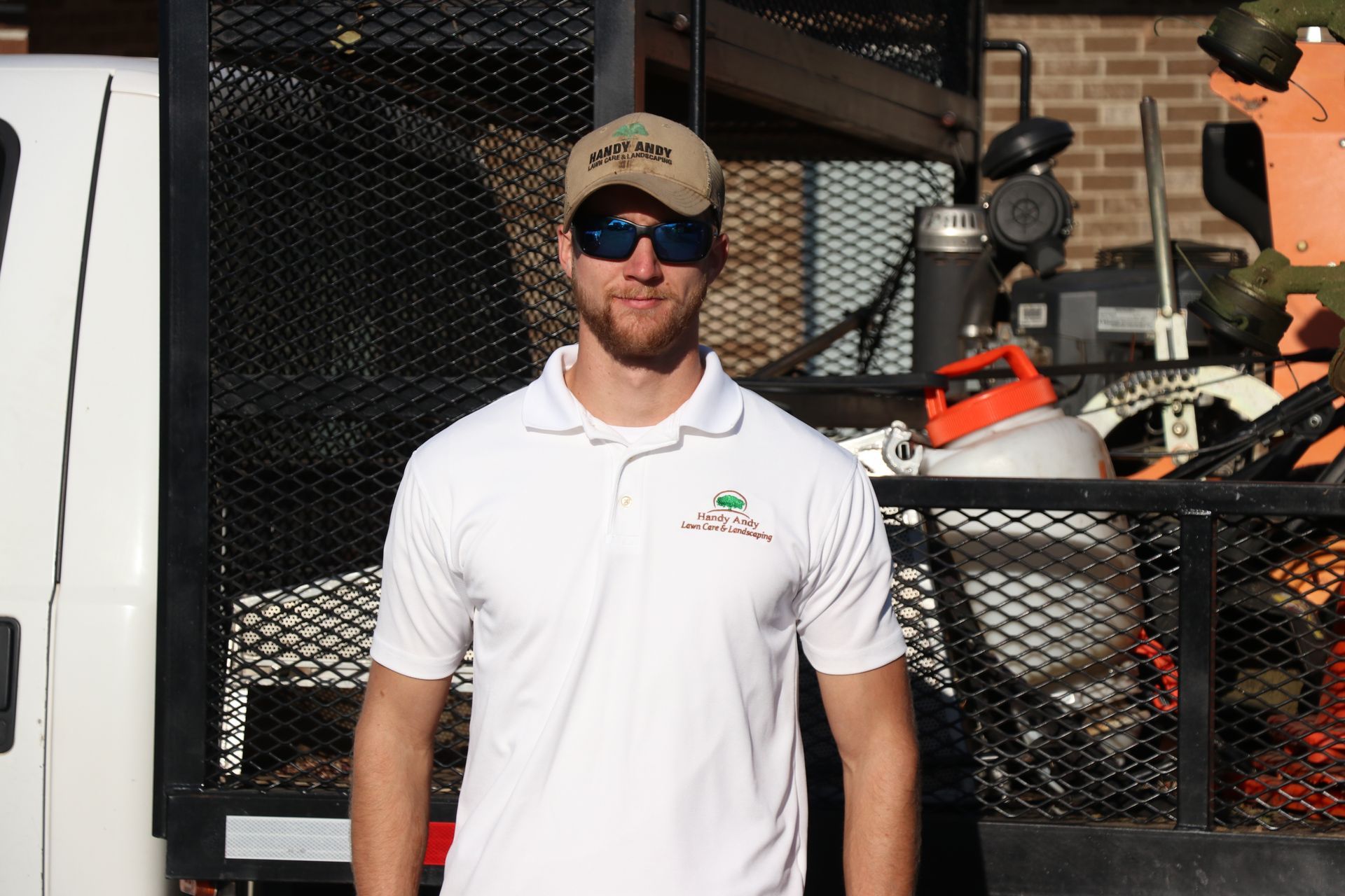 A man wearing sunglasses and a hat stands in front of a truck