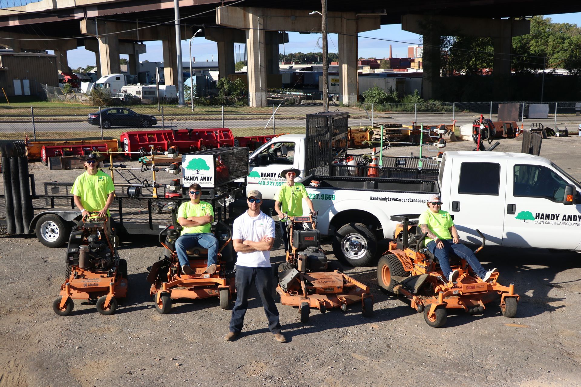 A group of people standing in front of a truck and lawn mowers.