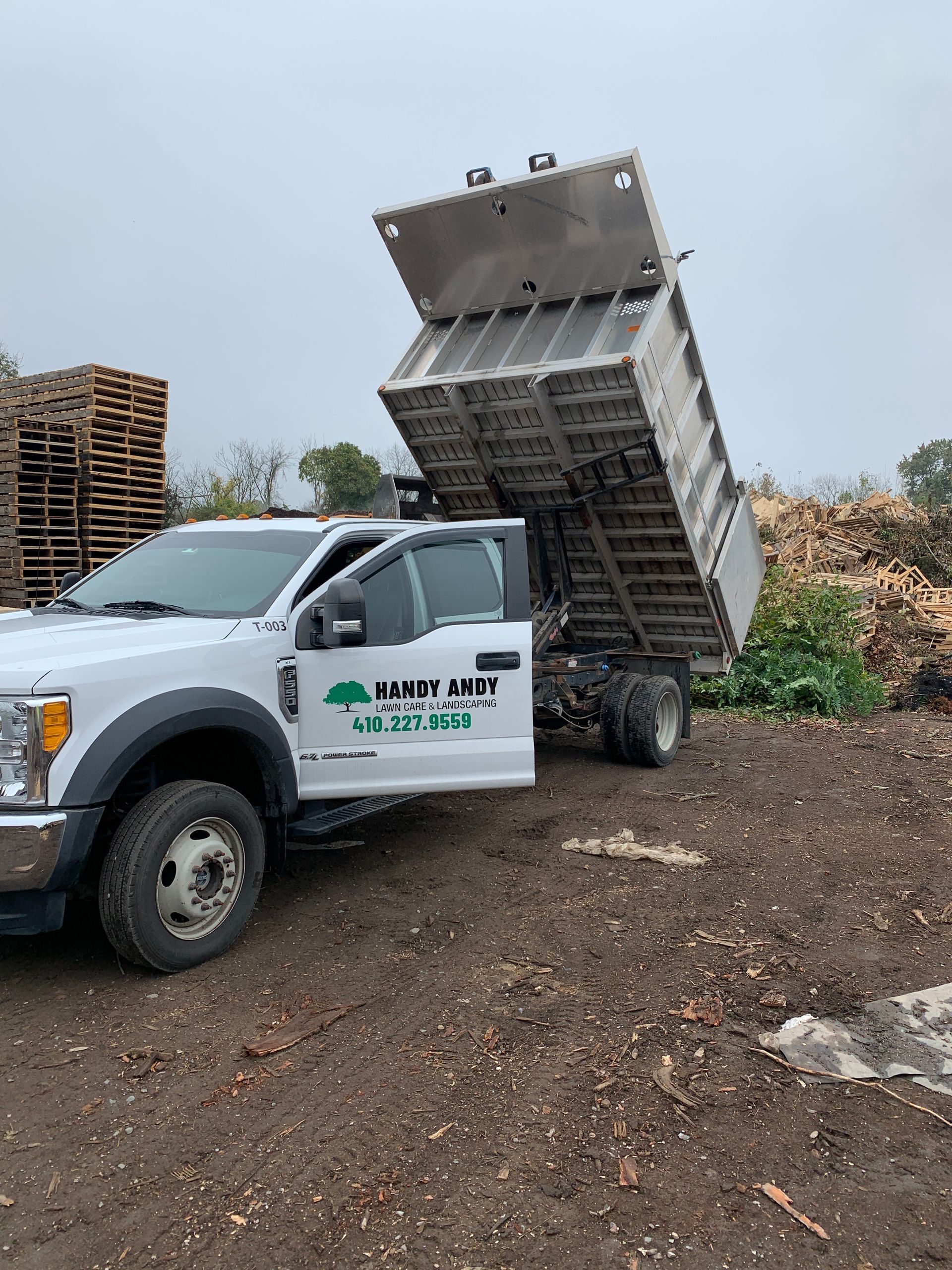 A dump truck is parked in a dirt field with its bed up.