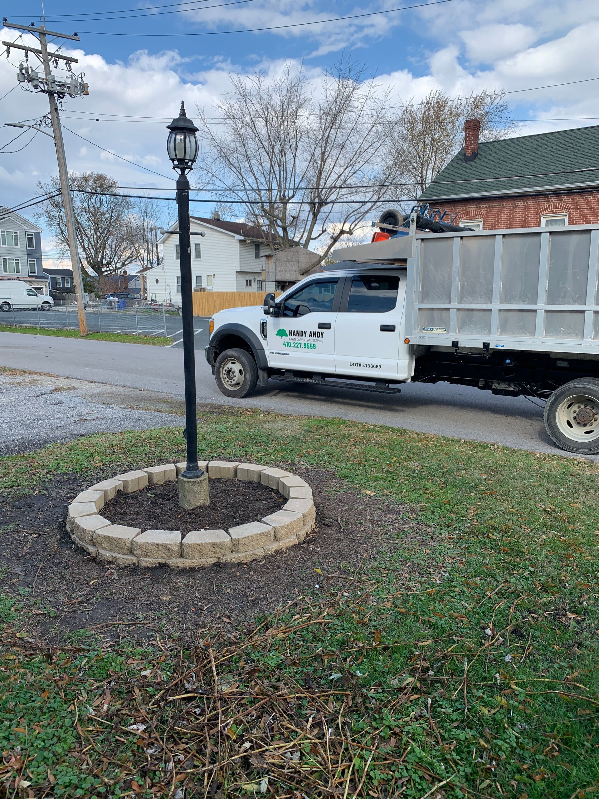 A white truck is parked on the side of the road next to a lamp post.