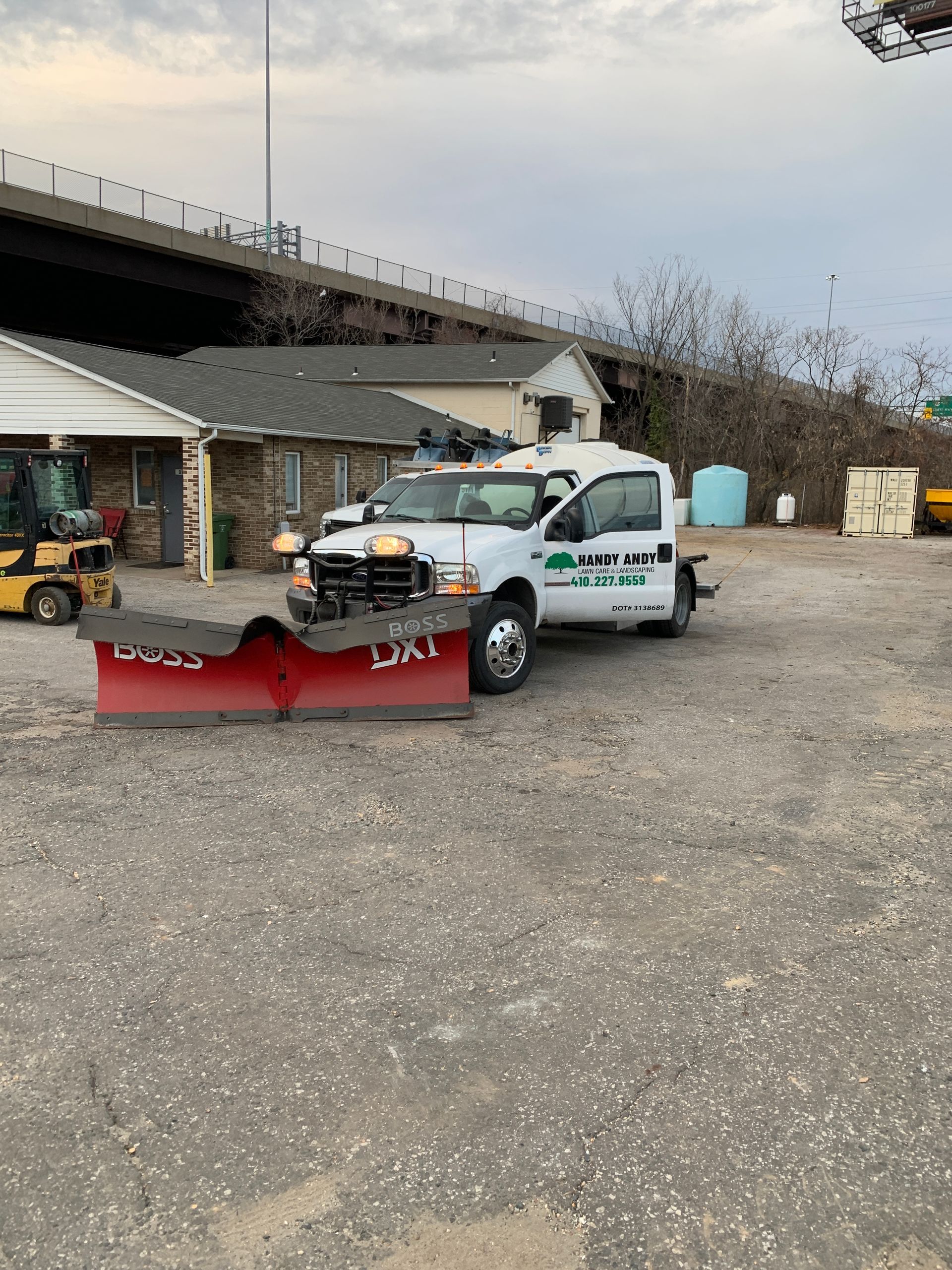 A snow plow is parked in a parking lot next to a house.