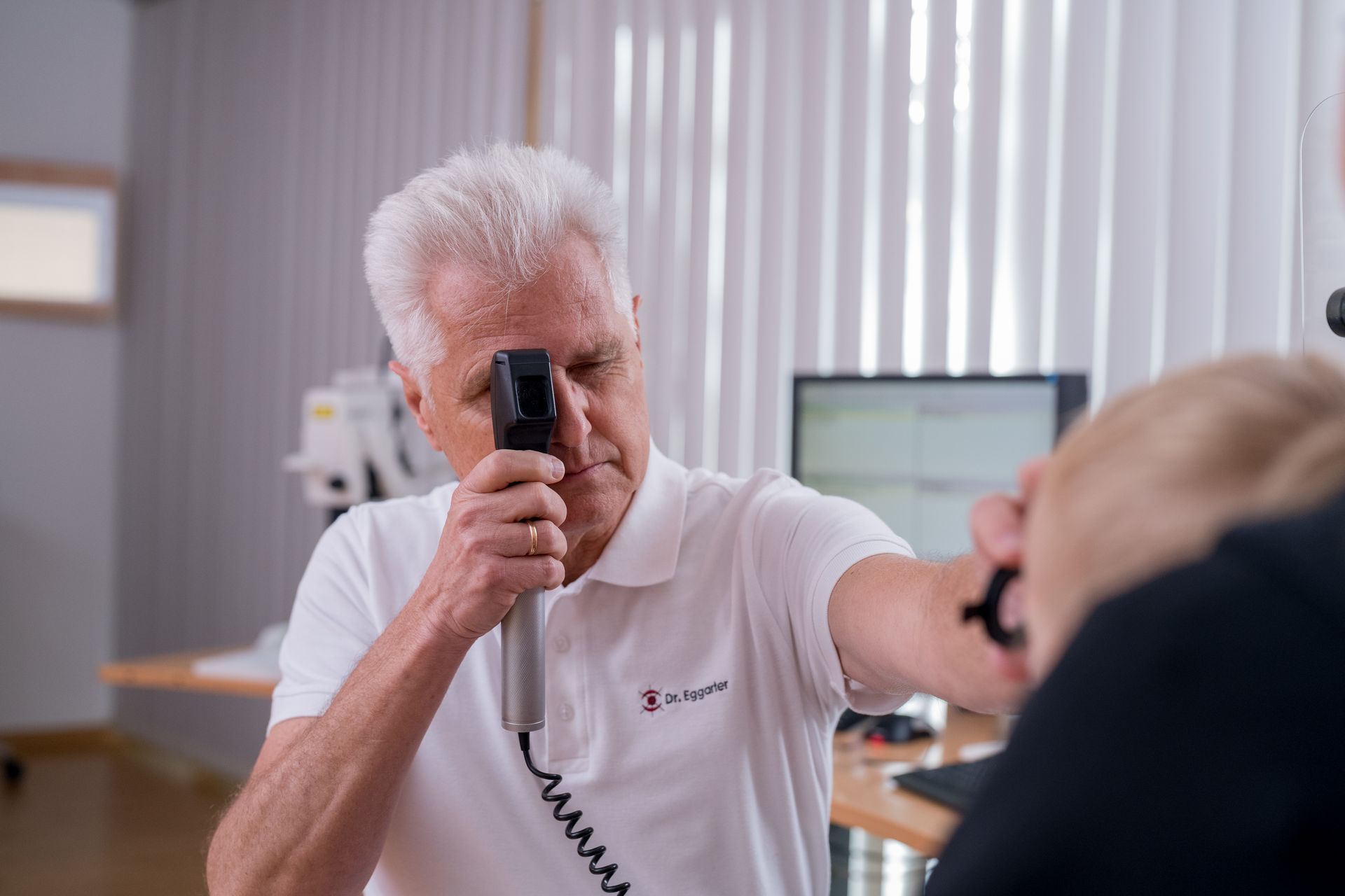 Facharzt der Augenarztpraxis in Feldkirch untersucht ein Kind