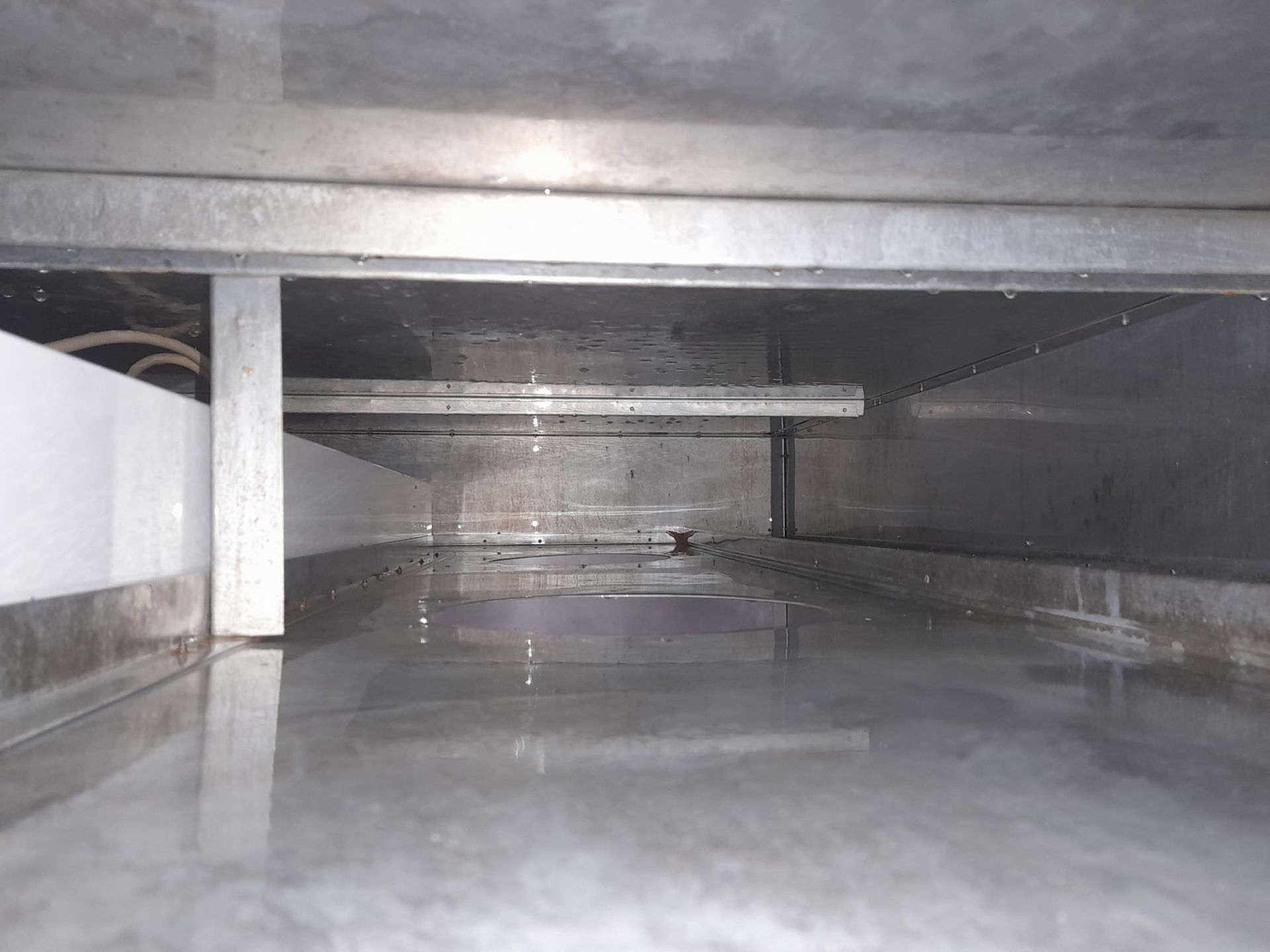 Das Innere eines Edelstahltanks mit austretendem Wasser.