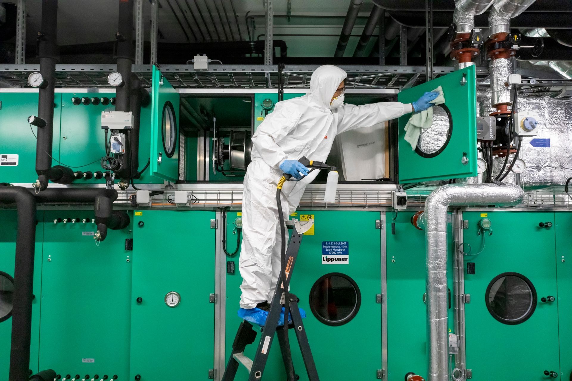 Ein Mann im Schutzanzug reinigt eine Maschine in einer Fabrik.