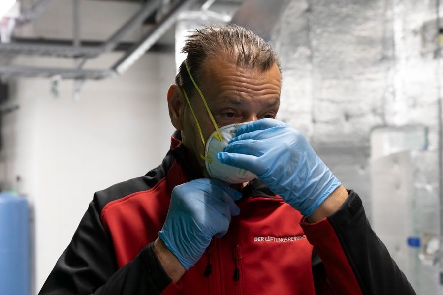 Drei Männer stehen in einem Raum und schauen etwas an