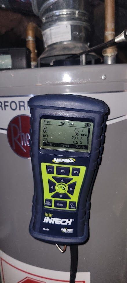 A Wohler Intech combustion analyzer attached to a Rheem water heater, displaying gas burner test readings.