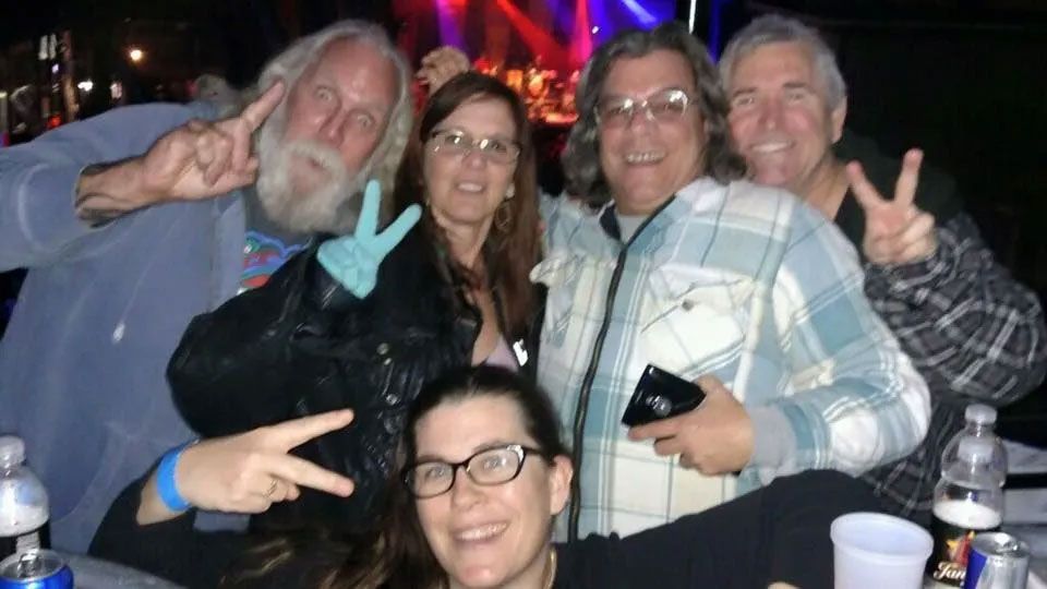 A group of people are posing for a picture and giving peace signs.