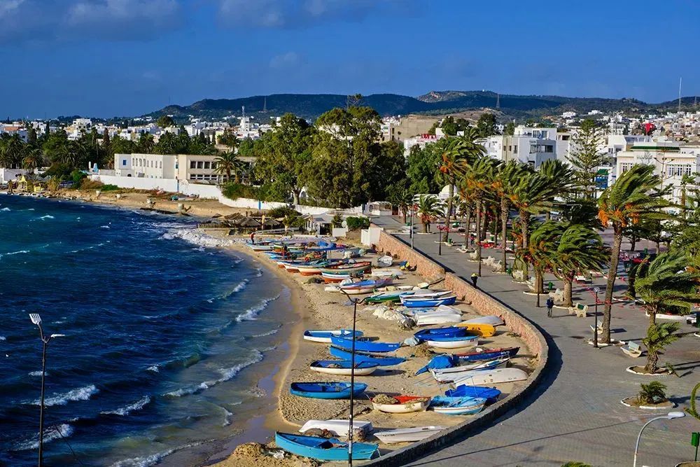 A beach with a lot of boats on it and a city in the background