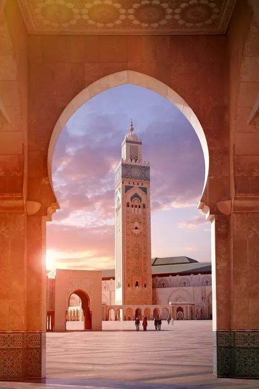 A clock tower is visible through an archway in a mosque.