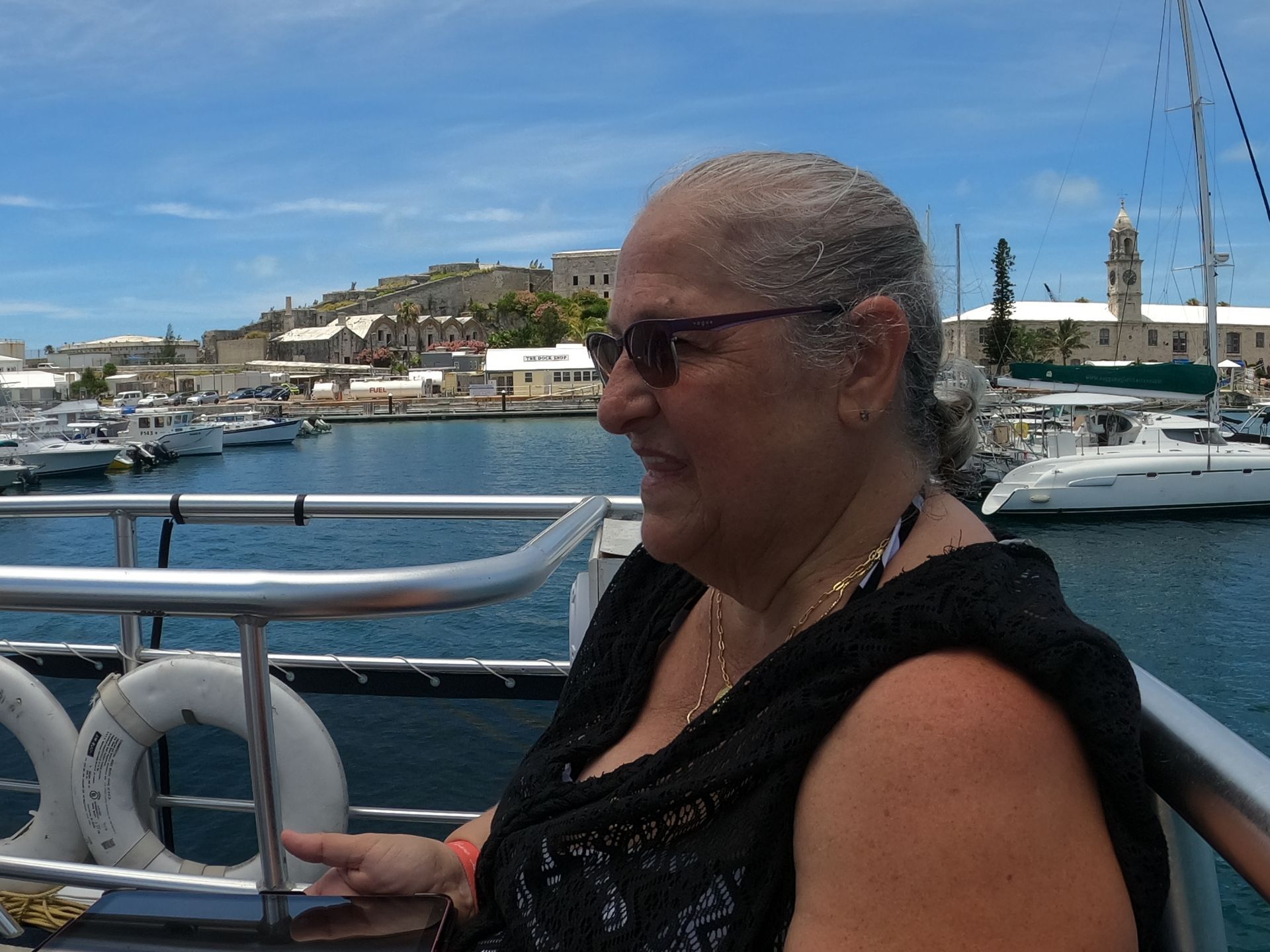 Woman on boat with harbor and buildings in background.
