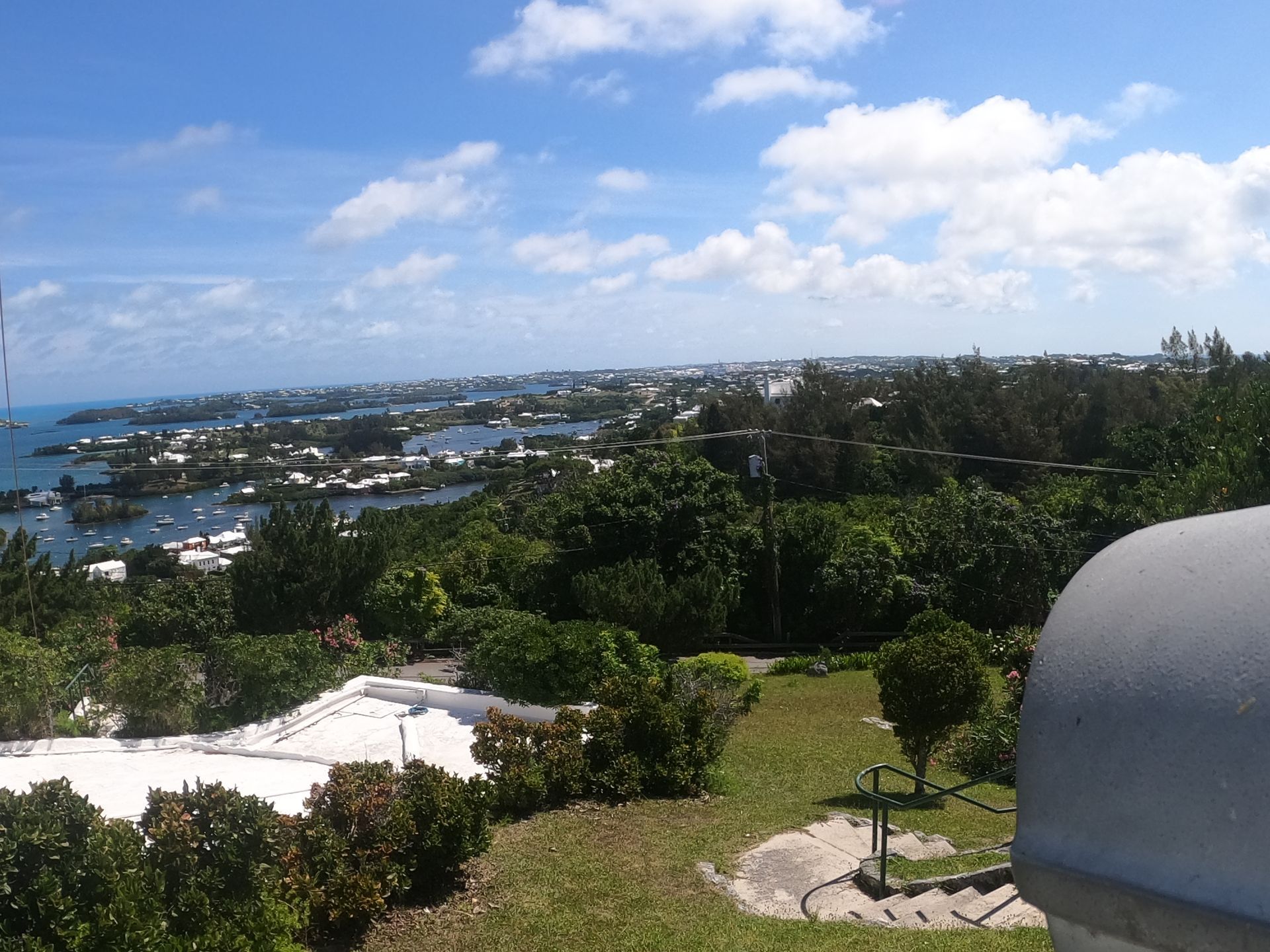 Overlooking Bermuda: green foliage, waterfront, town, and blue sky with clouds.