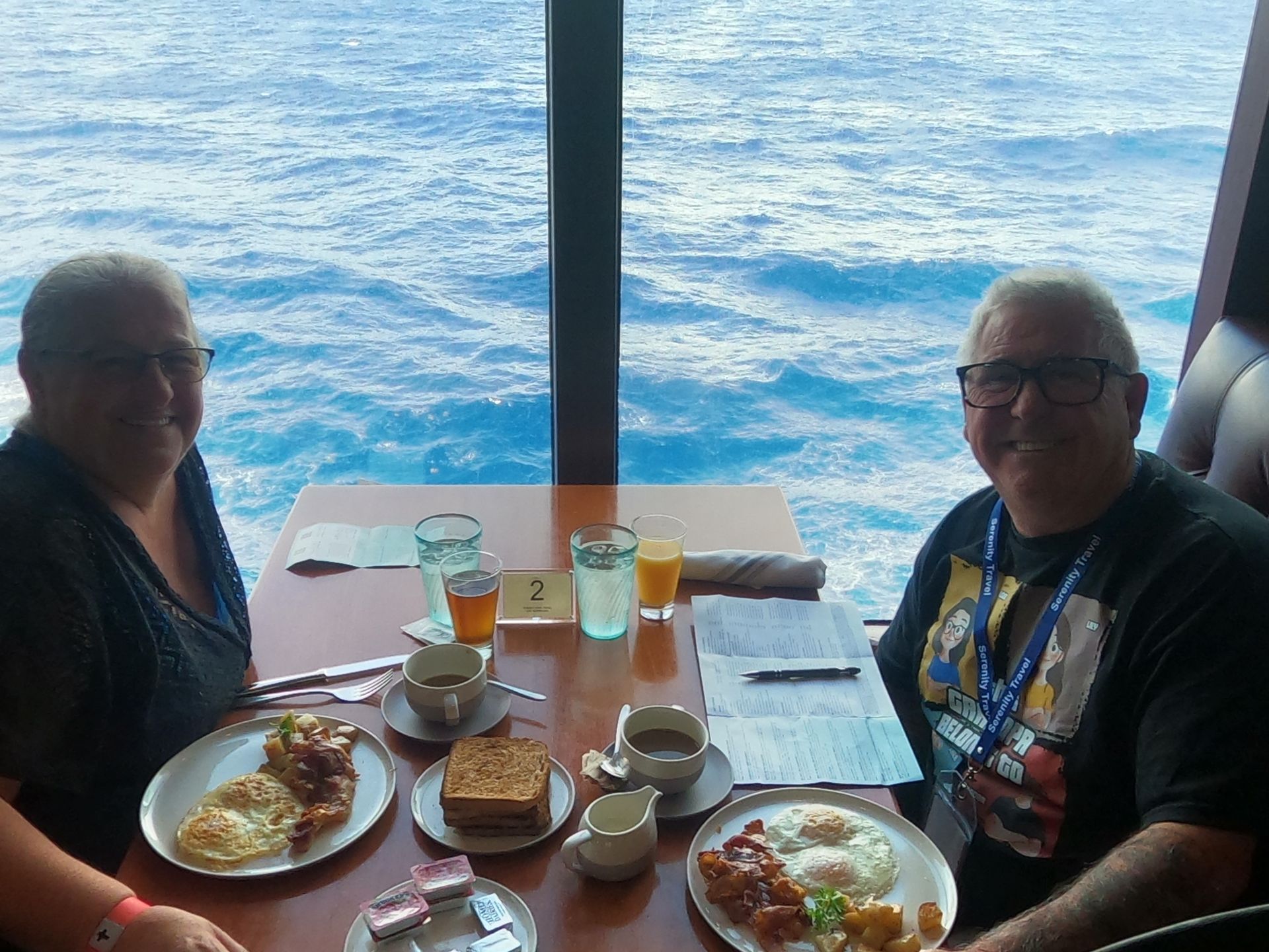 Two people enjoy breakfast with ocean view from inside a dining room.