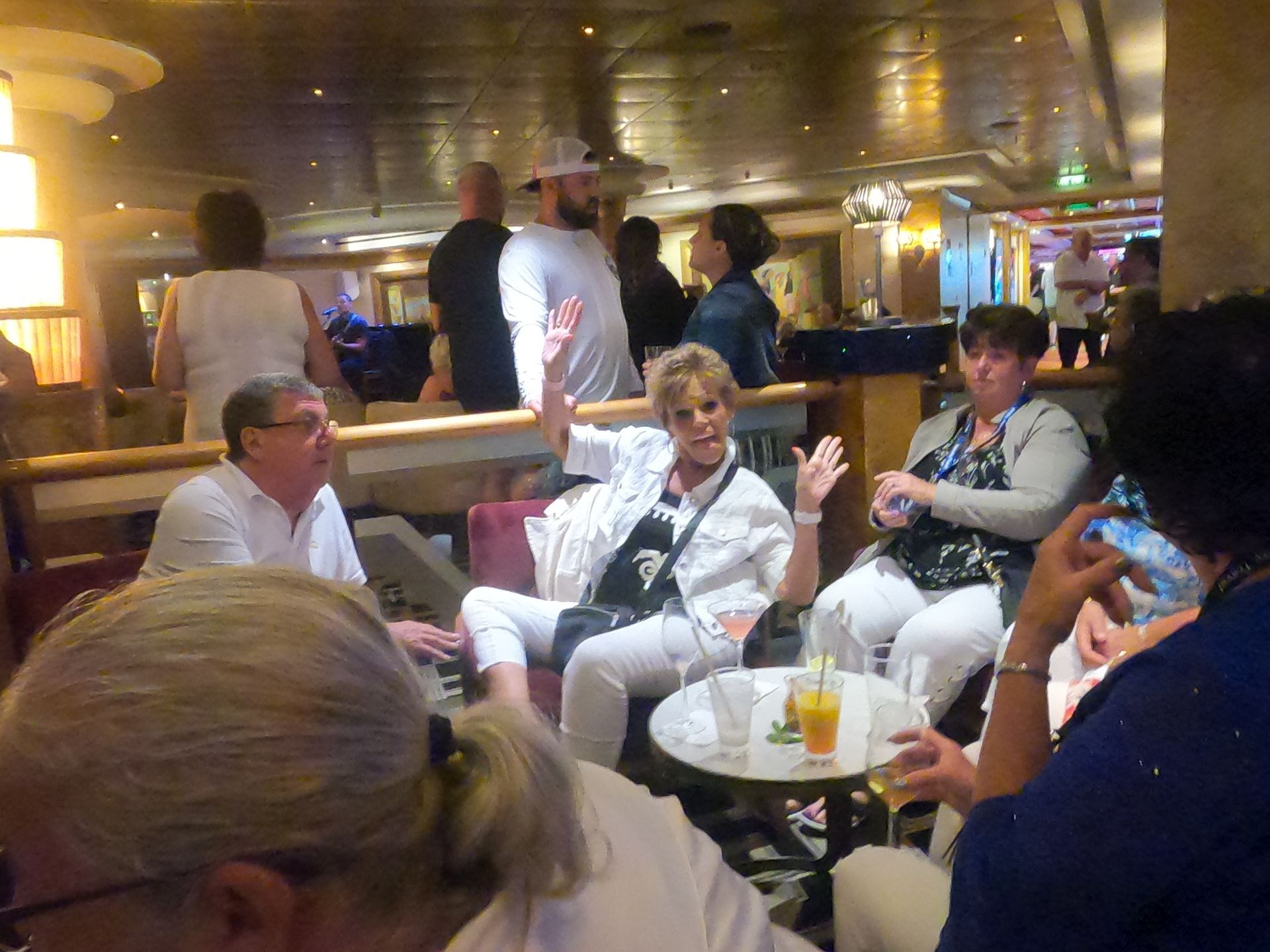 People socializing in a dimly lit lounge, including a woman gesturing enthusiastically while seated.