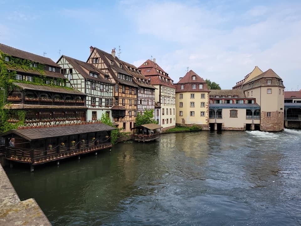 Historic buildings along a river in Strasbourg, France, with timber-framed houses and water flowing.