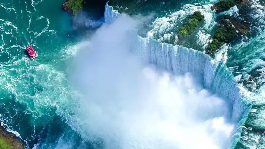 An aerial view of niagara falls with a boat in the water.