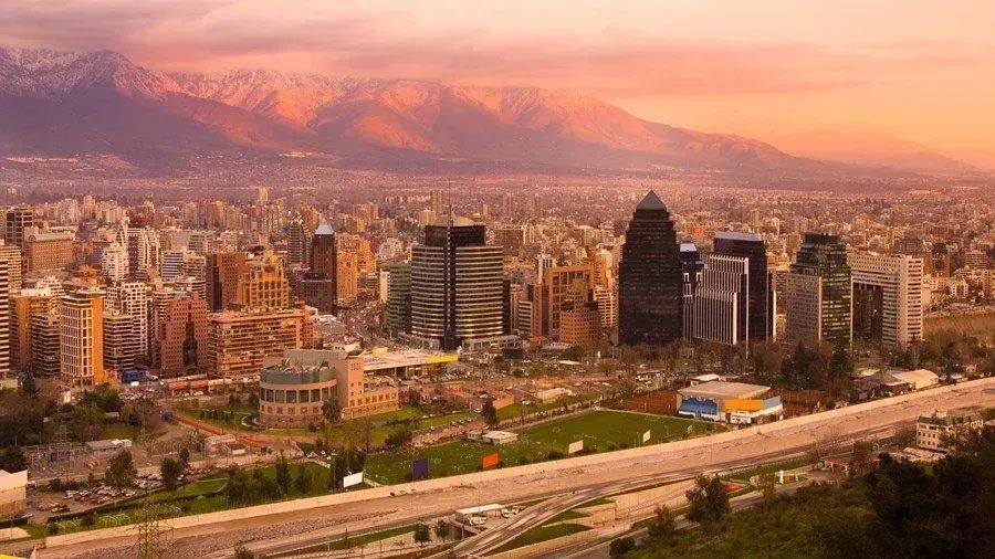 An aerial view of a city with mountains in the background at sunset.