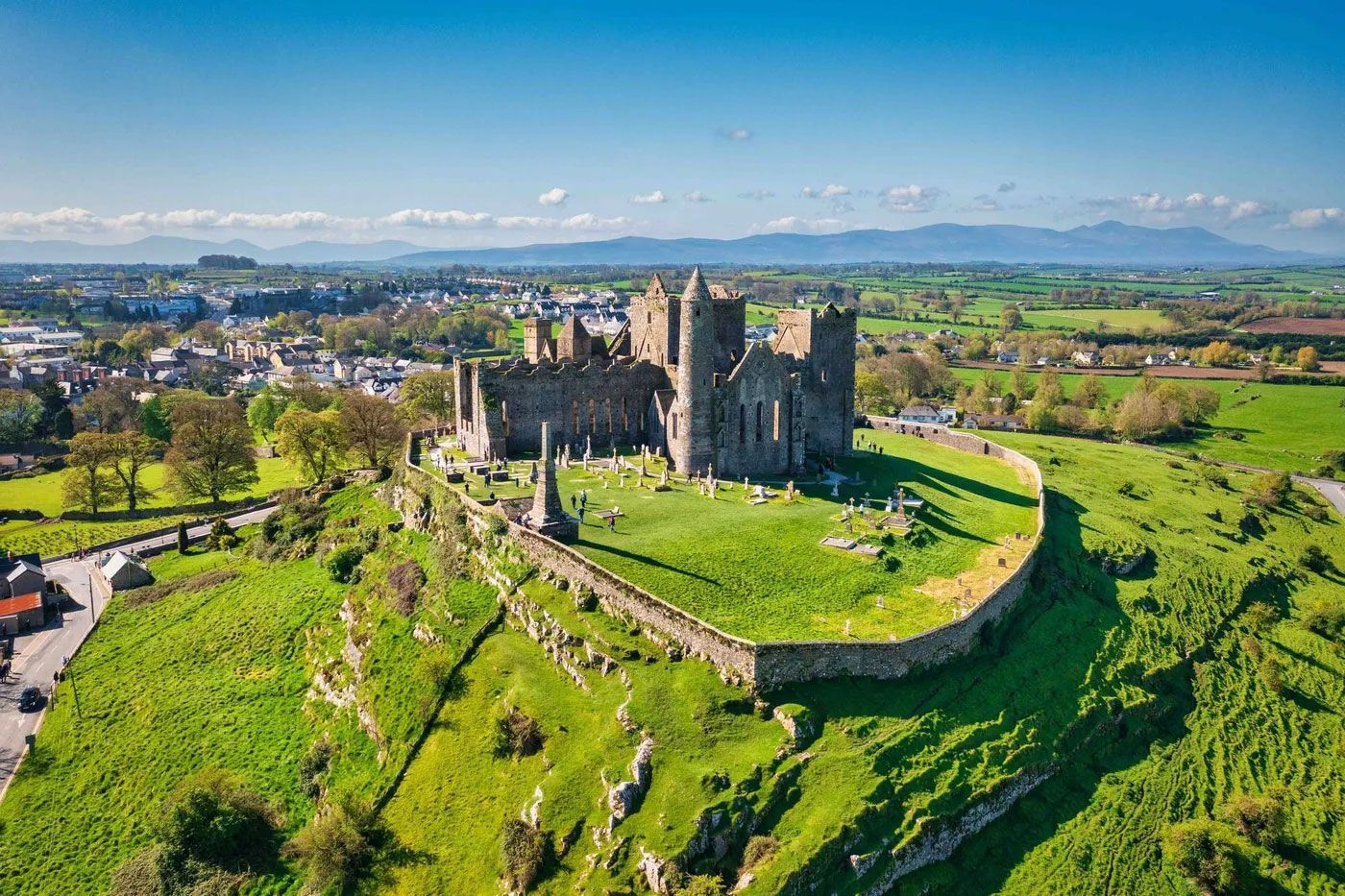 An aerial view of a castle on top of a grassy hill.