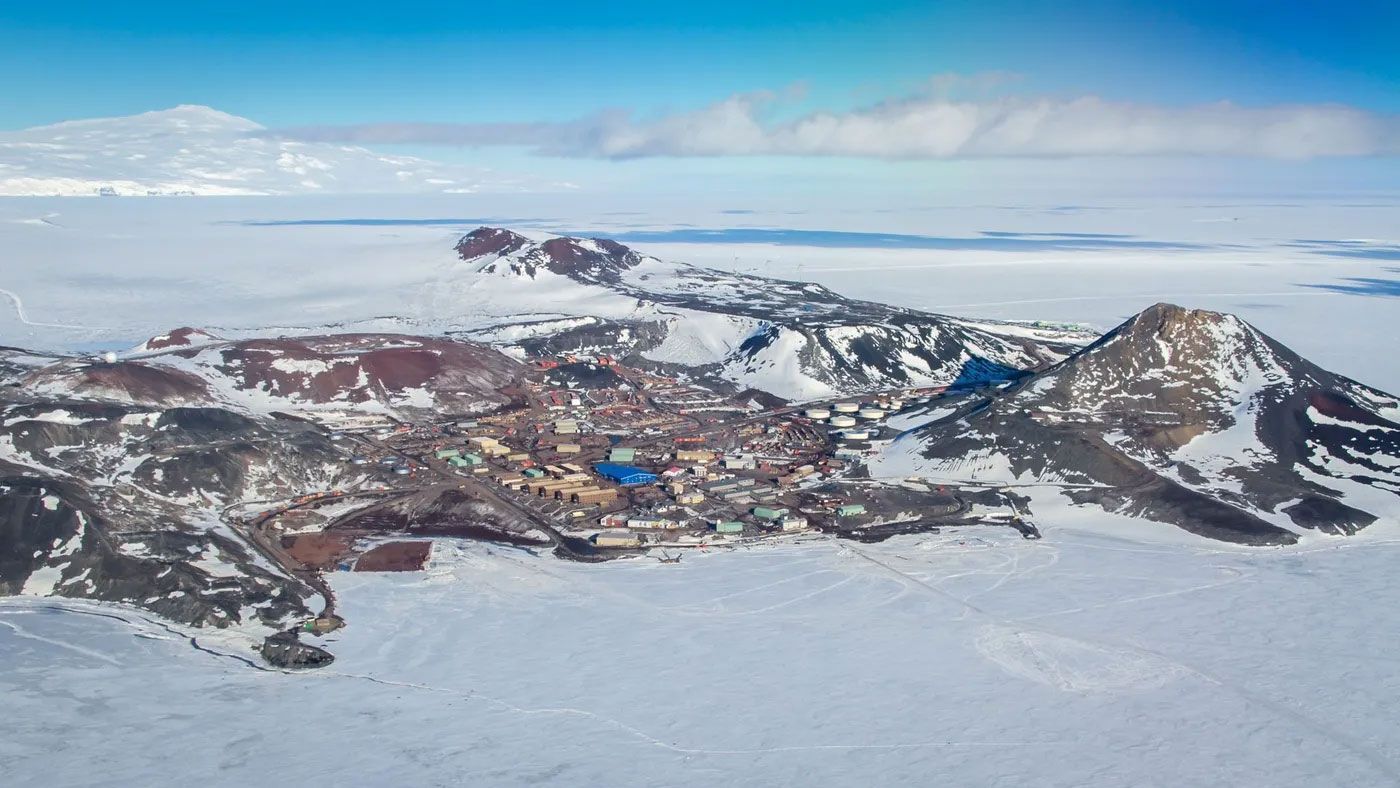 An aerial view of a snowy mountain range with a blue sky in the background.