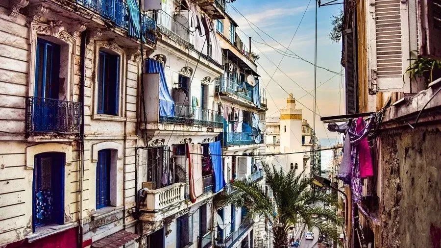 A city street with a lot of buildings and clothes hanging on the balconies.