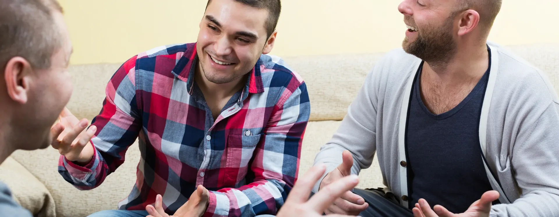 A group of men are sitting on a couch talking to each other.