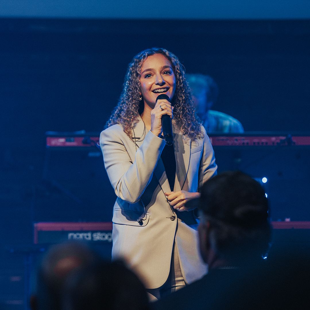 A woman in a suit is singing into a microphone